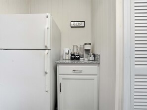A kitchen with a white refrigerator, a coffee maker, and a sign that says 'But first Coffee'. - 4 Min Downtown - 7 Min to Duke - 9 Min to Hospital (Durham)