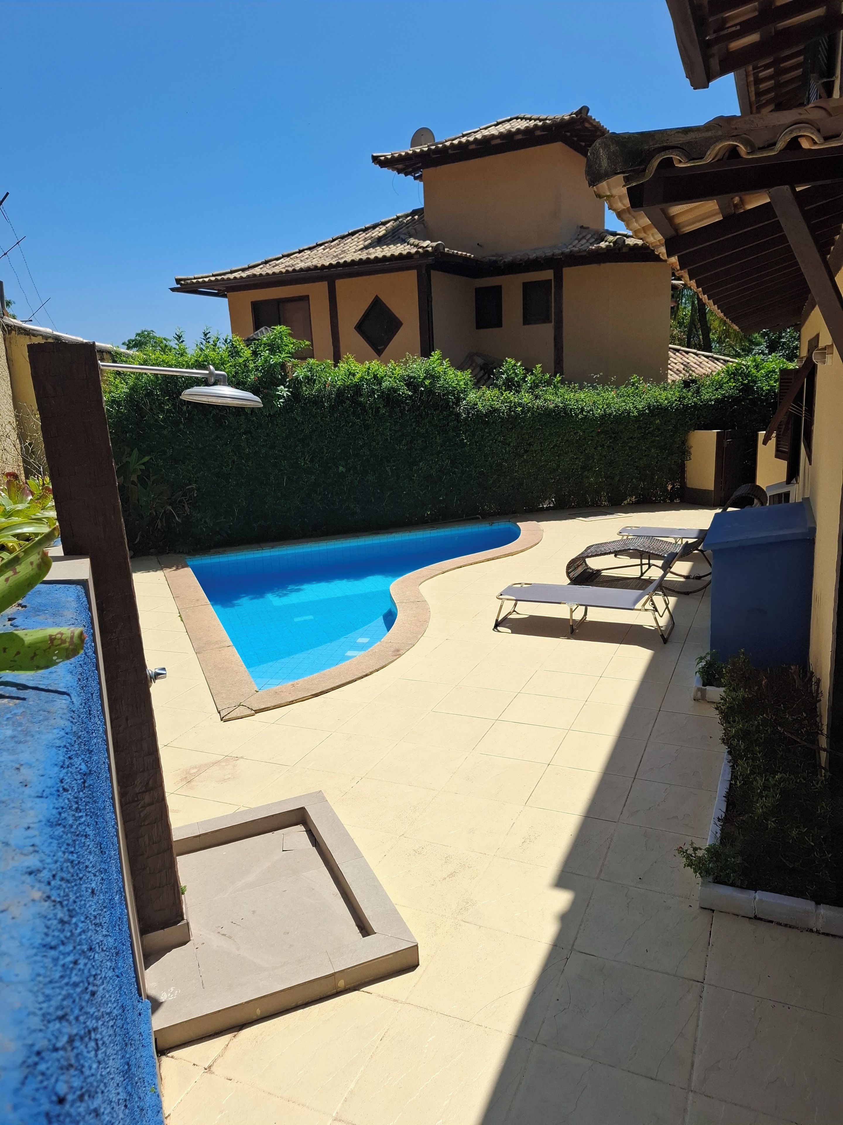 Ein Pool mit geschwungener Kante, umgeben von einer gefliesten Terrasse mit Liegestühlen.