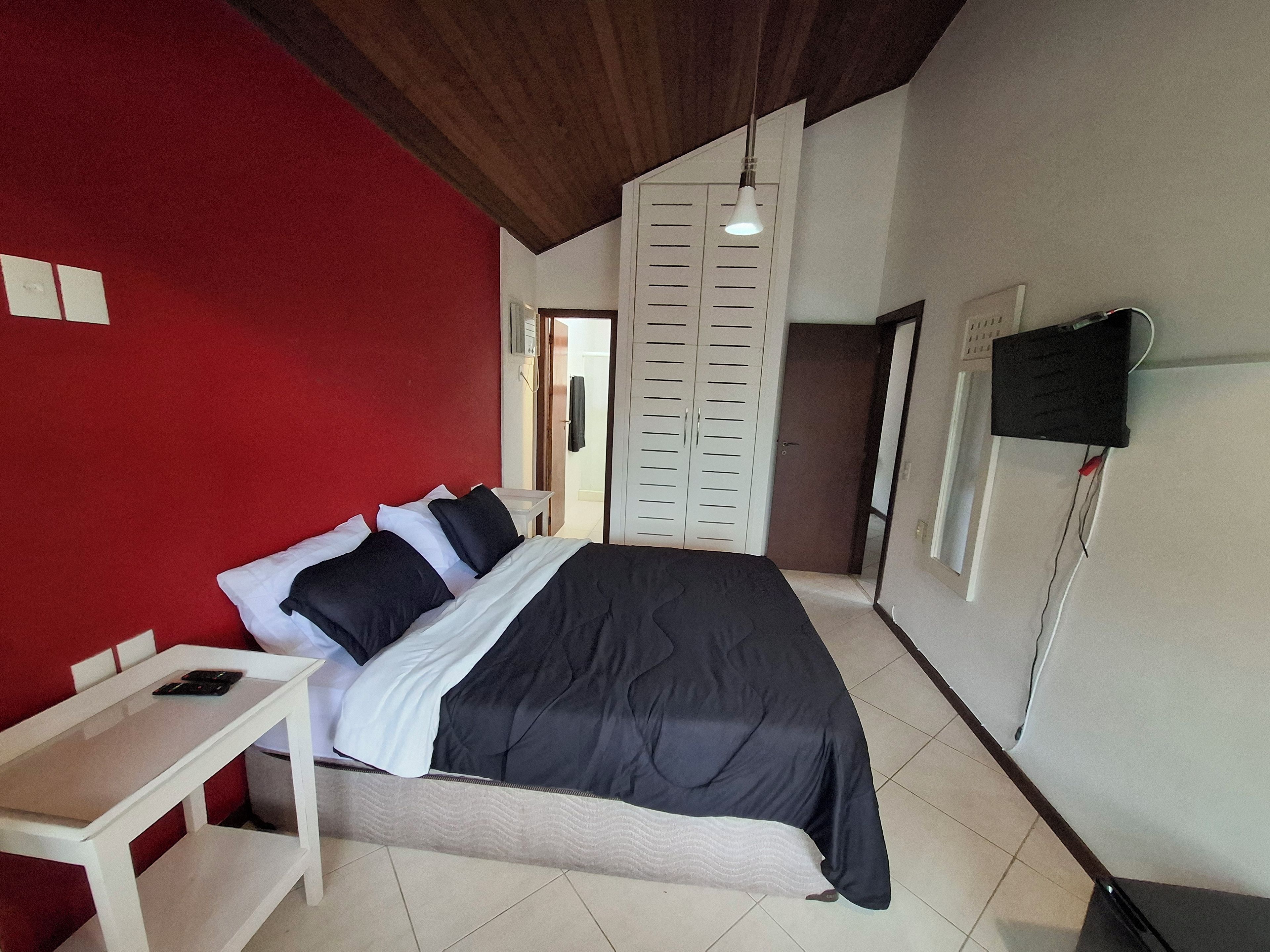 Ein Schlafzimmer mit einem Bett, einem Nachttisch, einem Kleiderschrank und einer Hängeleuchte.