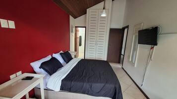 Ein Schlafzimmer mit einem Bett, einem Nachttisch, einem Kleiderschrank und einer Hängeleuchte.