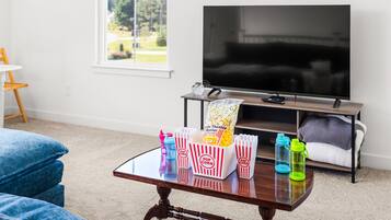 Bright living room with big-screen TV, natural light, and cozy movie-night setup