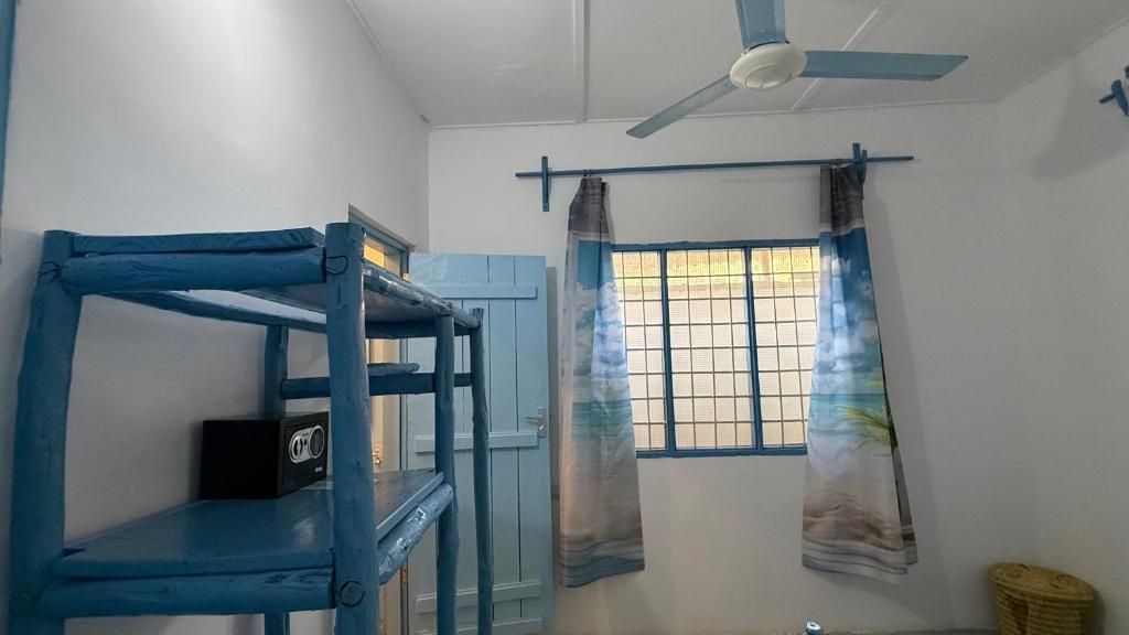 A room with bunk beds, a ceiling fan, a window with curtains, and a door.