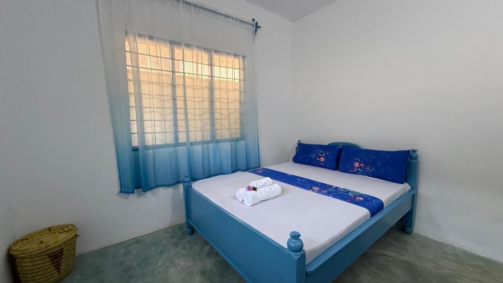 A single bed with a blue headboard and a white mattress, a blue bedspread, and a white towel on the bed.