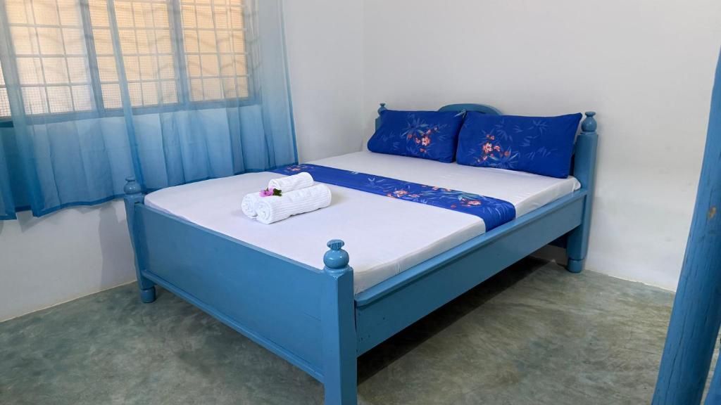 Una cama individual con cabecera y piecera azules, colchón blanco y colcha azul.