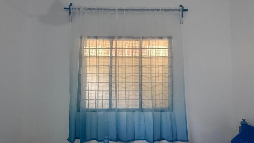 A window with a grid pattern and a blue curtain.