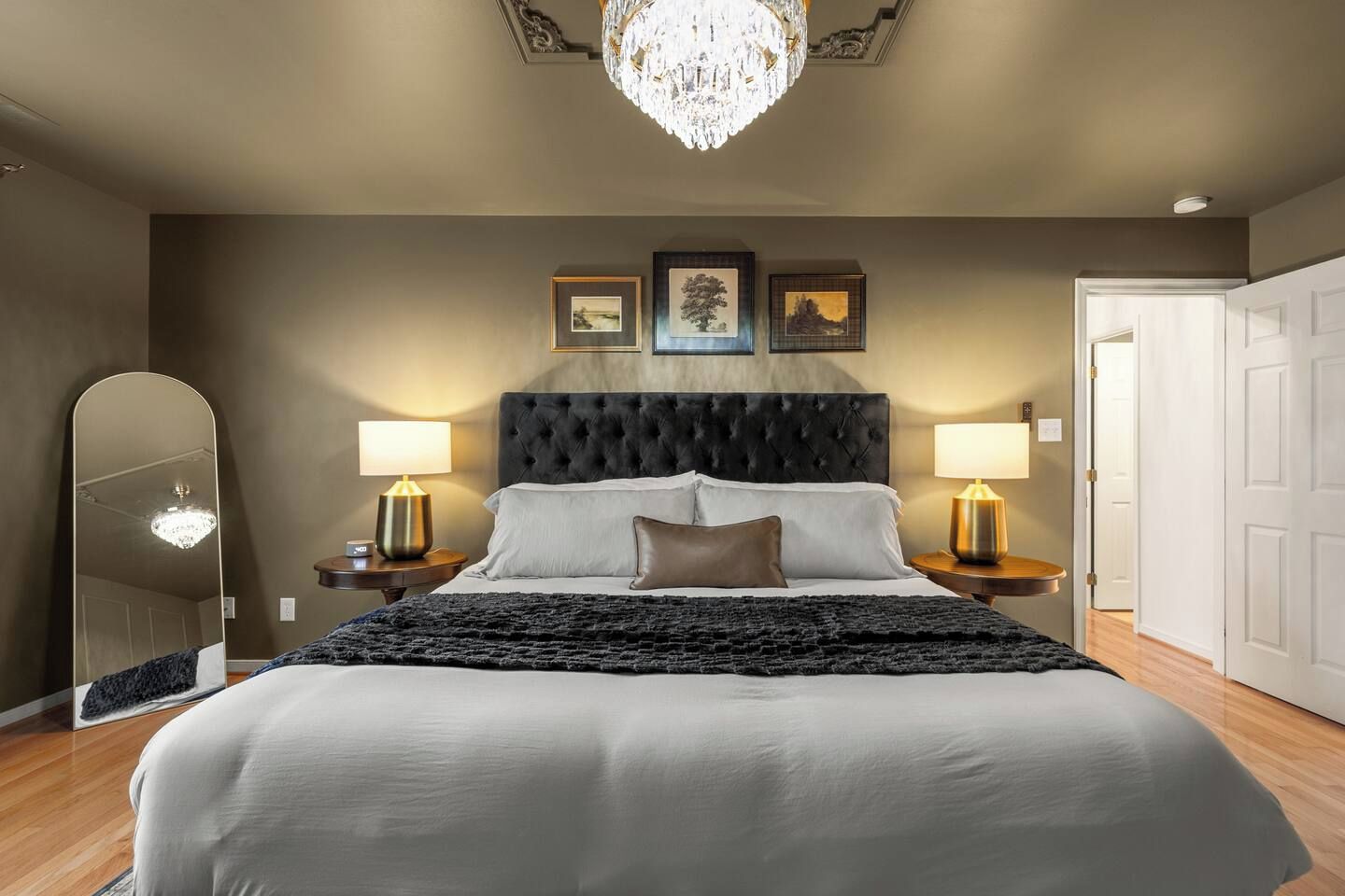 Una camera da letto con un letto grande, due lampade ai piedi del letto, un lampadario e quadri appesi alle pareti.