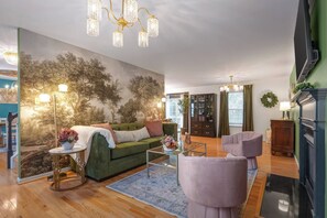 Een woonkamer met een groene bank, een salontafel en een open haard.