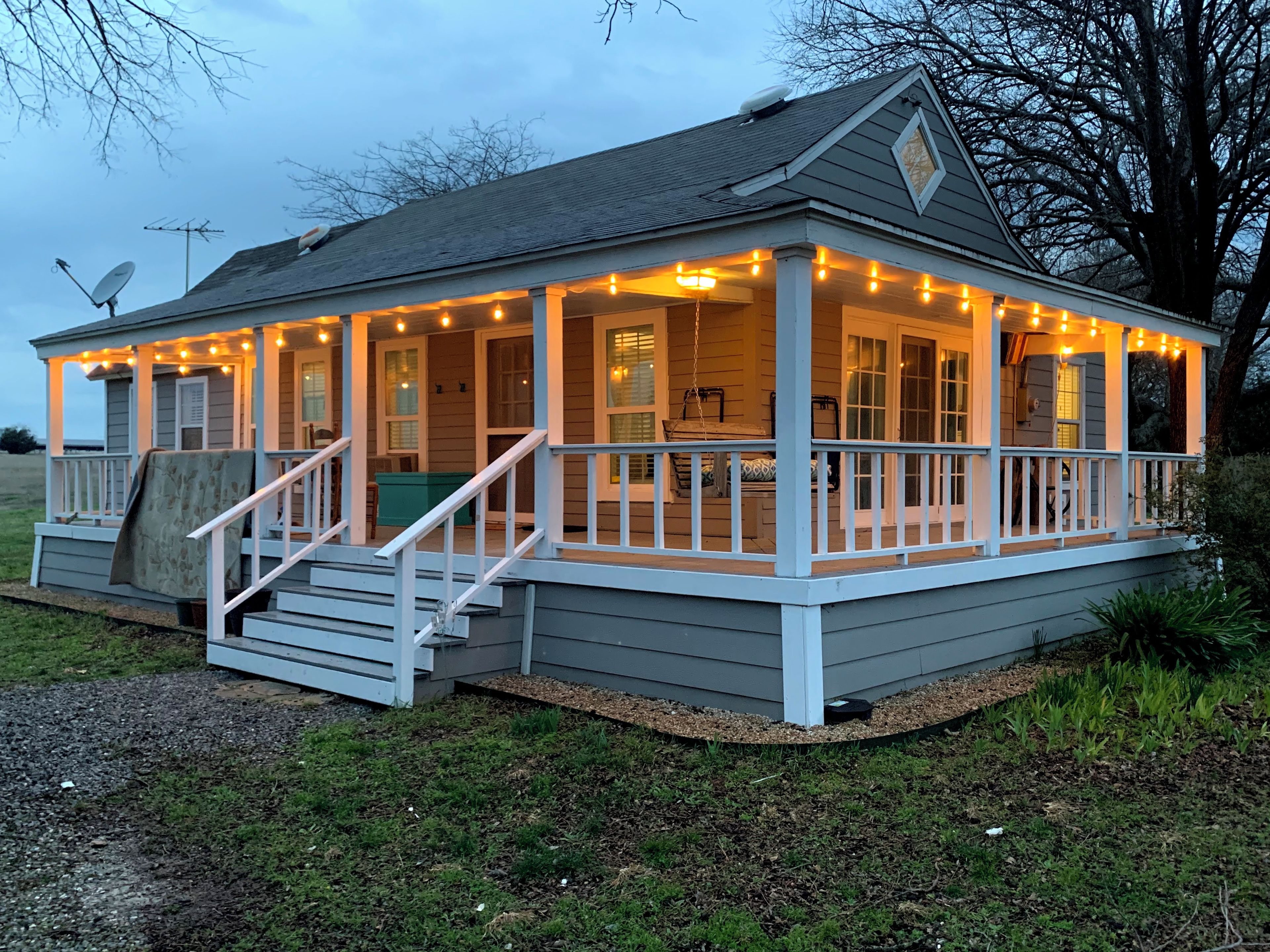 A house with a porch, steps, and string lights.