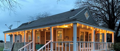 A house with a porch, steps, and string lights.