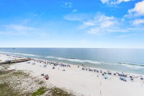 A beach with a pier, umbrellas, and beach chairs. - San Carlos 1003 (Gulf Shores)