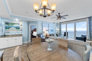 A spacious living area with a large round table, a sofa set, a ceiling fan, and a view of the ocean. - San Carlos 1003 (Gulf Shores)