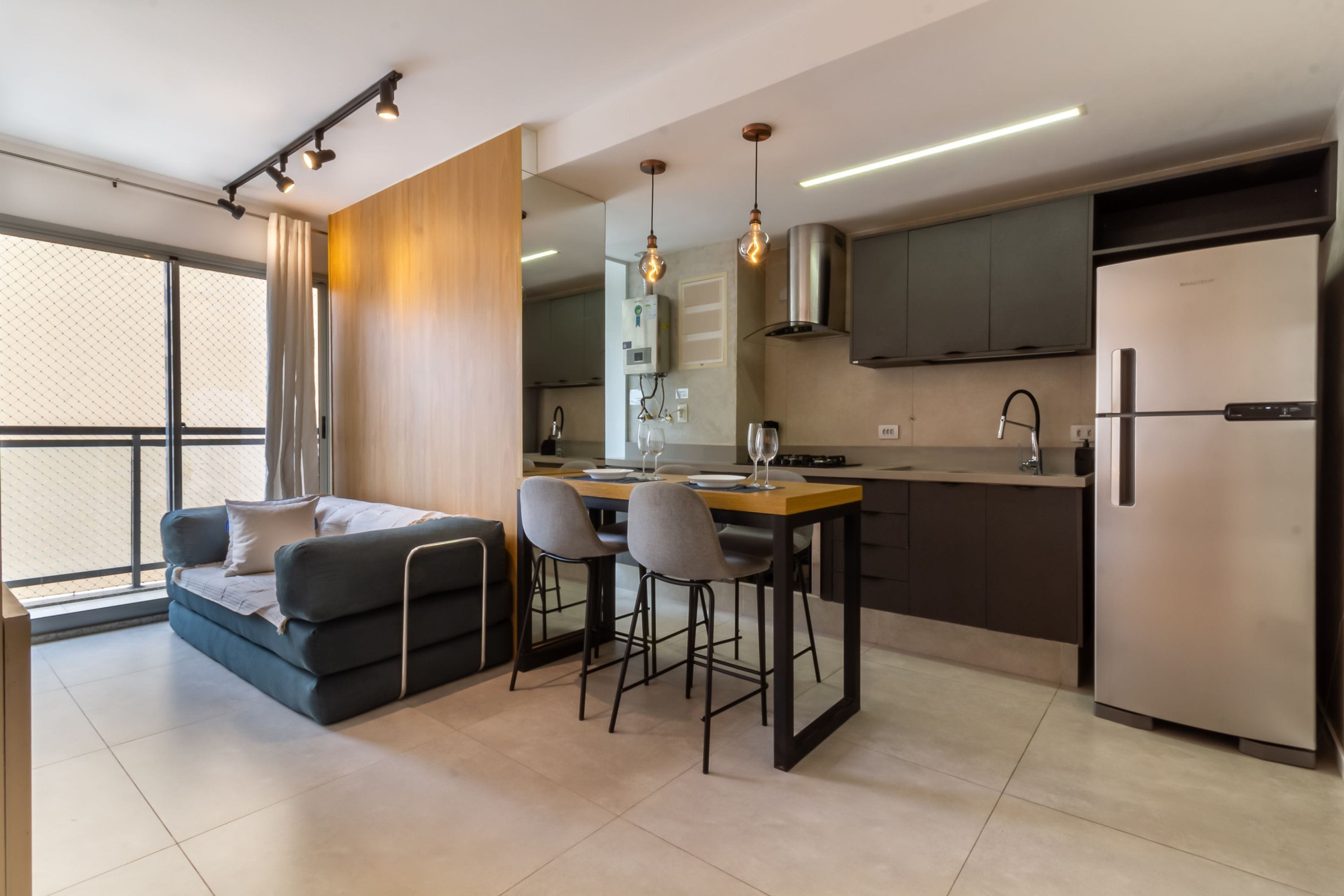 A modern kitchen with a dining area, a sofa, and a refrigerator.