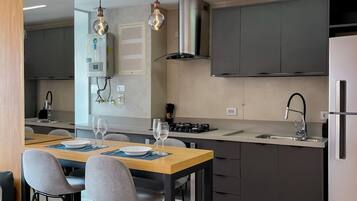 A modern kitchen with a central island, two bar stools, a built-in oven, and a stainless steel refrigerator.
