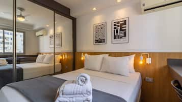 A hotel room with a bed, a mirror, wall-mounted artwork, and a ceiling fan.