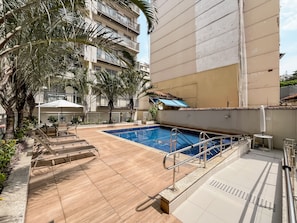 A swimming pool with a sunshade, surrounded by palm trees and a building with balconies. - 1BR Apt With Pool Gym in Downtown Rio - Rz513 (Rio de Janeiro)