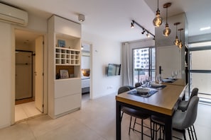 Una cocina moderna con comedor, estanterías integradas e iluminación colgante.
