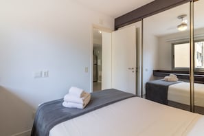 A hotel room with a bed, a bedside table, a mirror, and a door leading to another room. - 1BR Apt With Pool Gym in Downtown Rio - Rz513 (Rio de Janeiro)