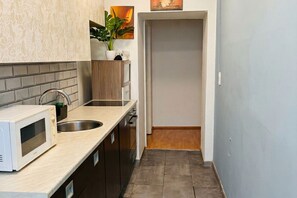 A compact kitchen with a microwave, sink, and wooden cabinets. - Bring Everyone 3BR near Belvedere Palace (Vienna)
