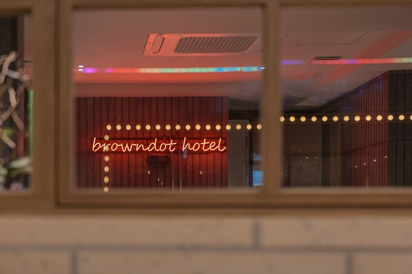 A window view of a room with a neon sign reading 'browndot hotel' and a brick wall. - Browndot Sinchon (Seoul)