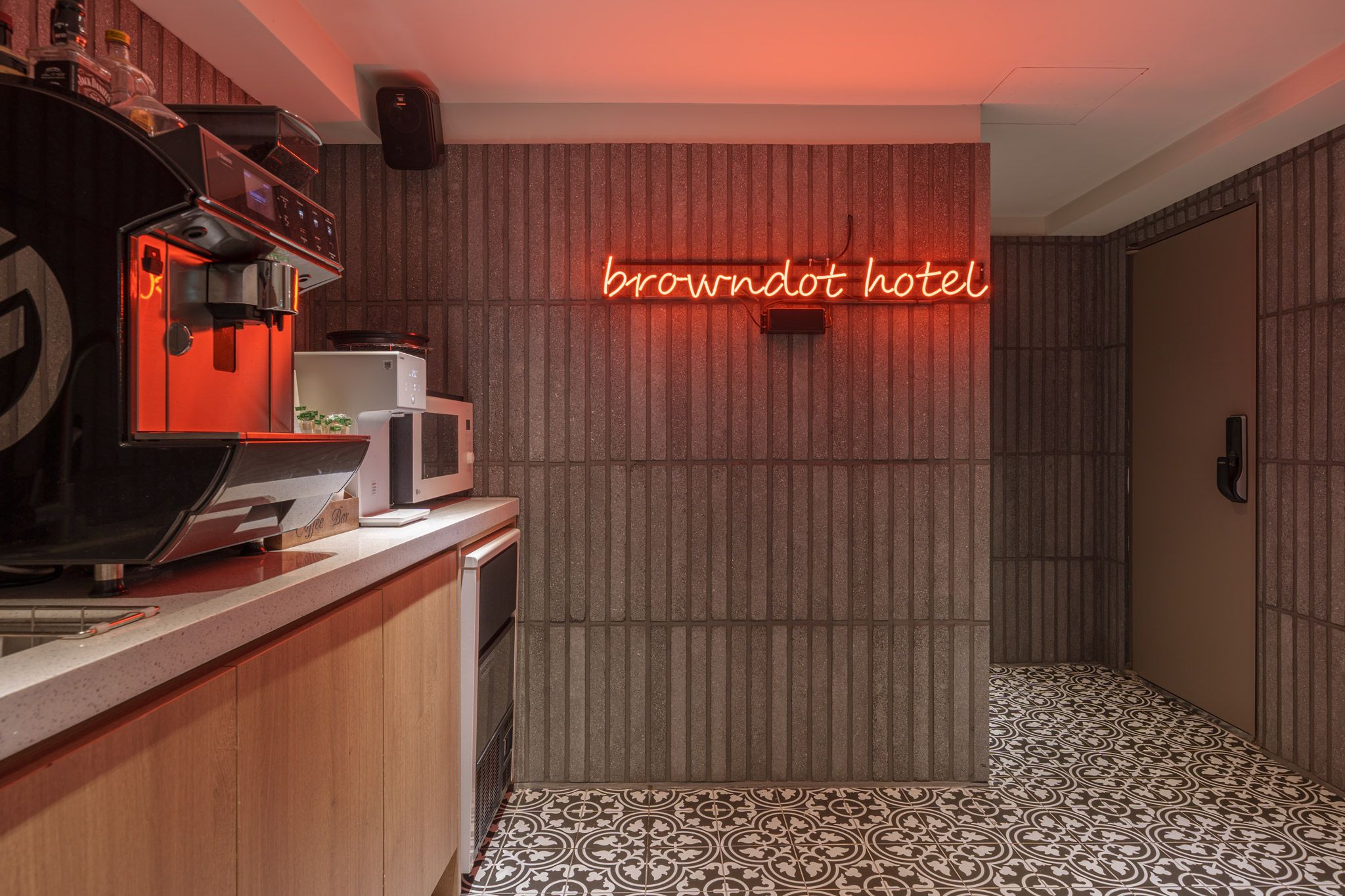 Uma cozinha equipada com micro-ondas, máquina de café e um letreiro de neon que diz 'browndot hotel'.