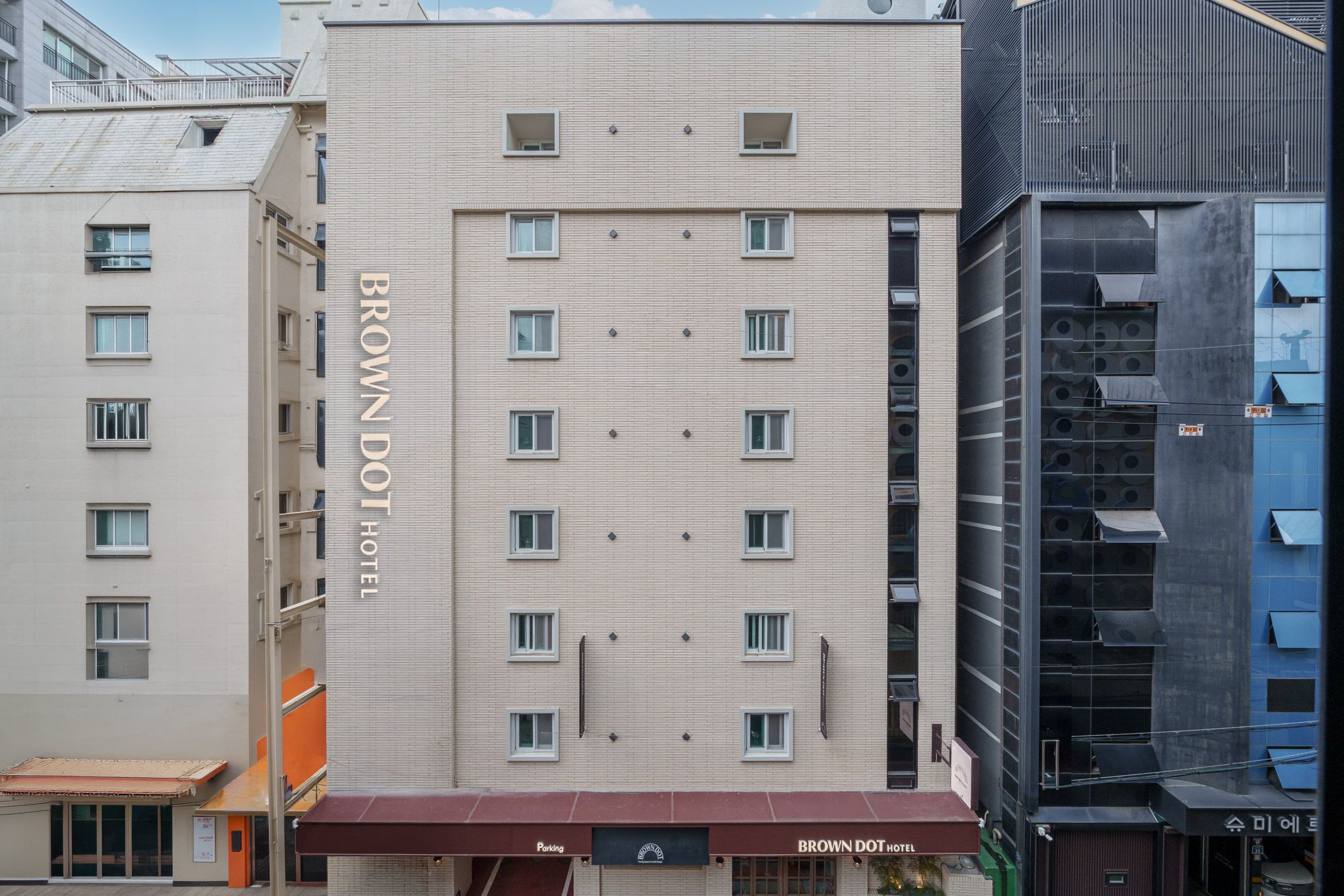 A multi-story hotel building with a prominent 'BROWN DOT HOTEL' sign on the facade.