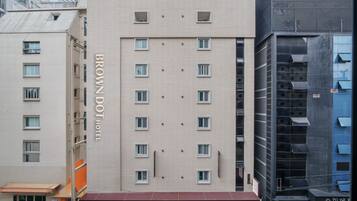 Un immeuble d’hôtel à plusieurs étages, dont la façade est ornée d’une grande enseigne indiquant « BROWN DOT HOTEL ».