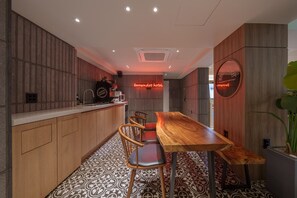 A modern kitchen with a wooden table and chairs, a coffee machine, and a neon sign. - Browndot Hongdae Sinchon (Seoul)