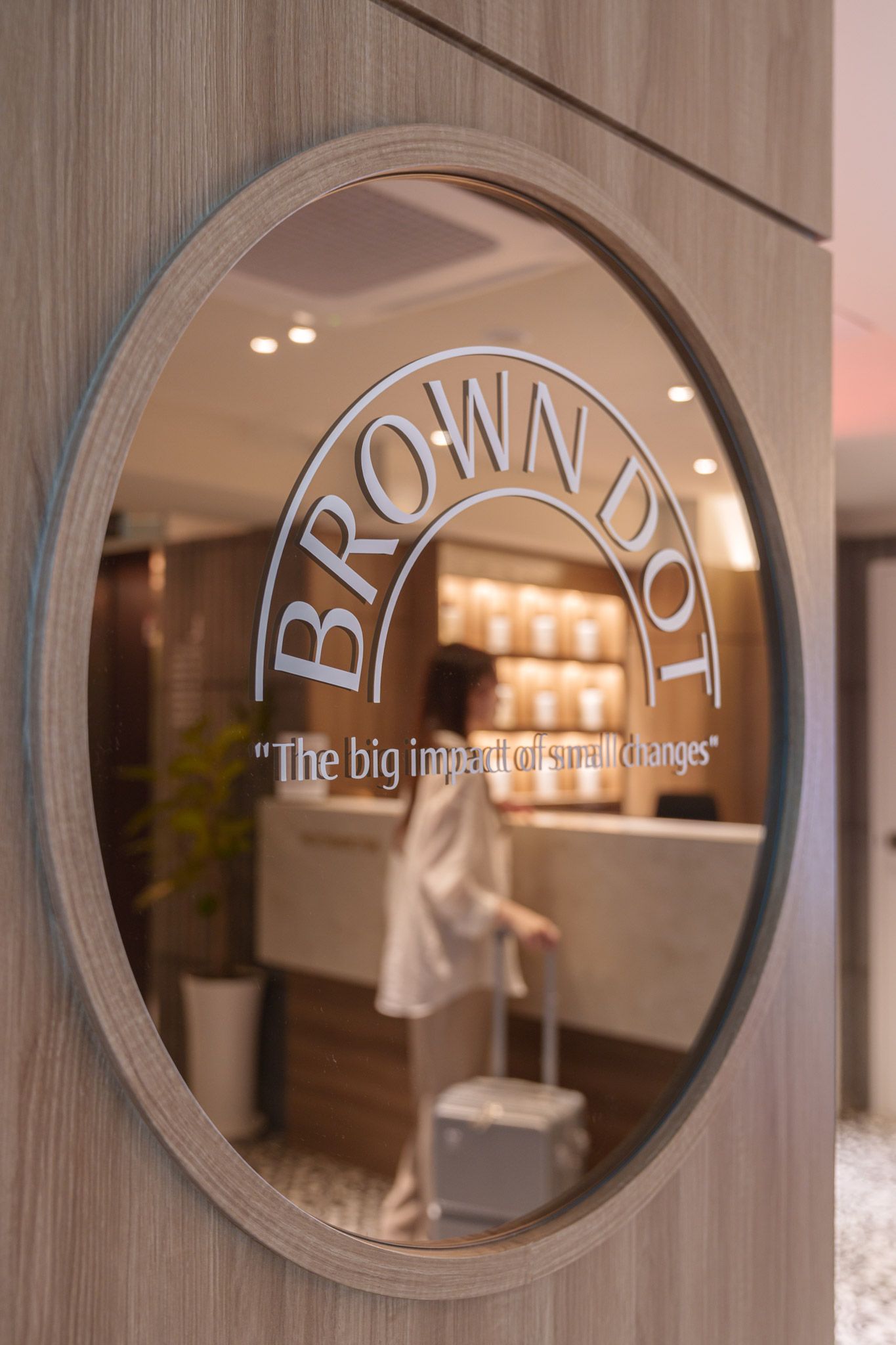 A circular sign with the text 'BROWN DOT' and a tagline 'The big impact of small changes' on a building facade.