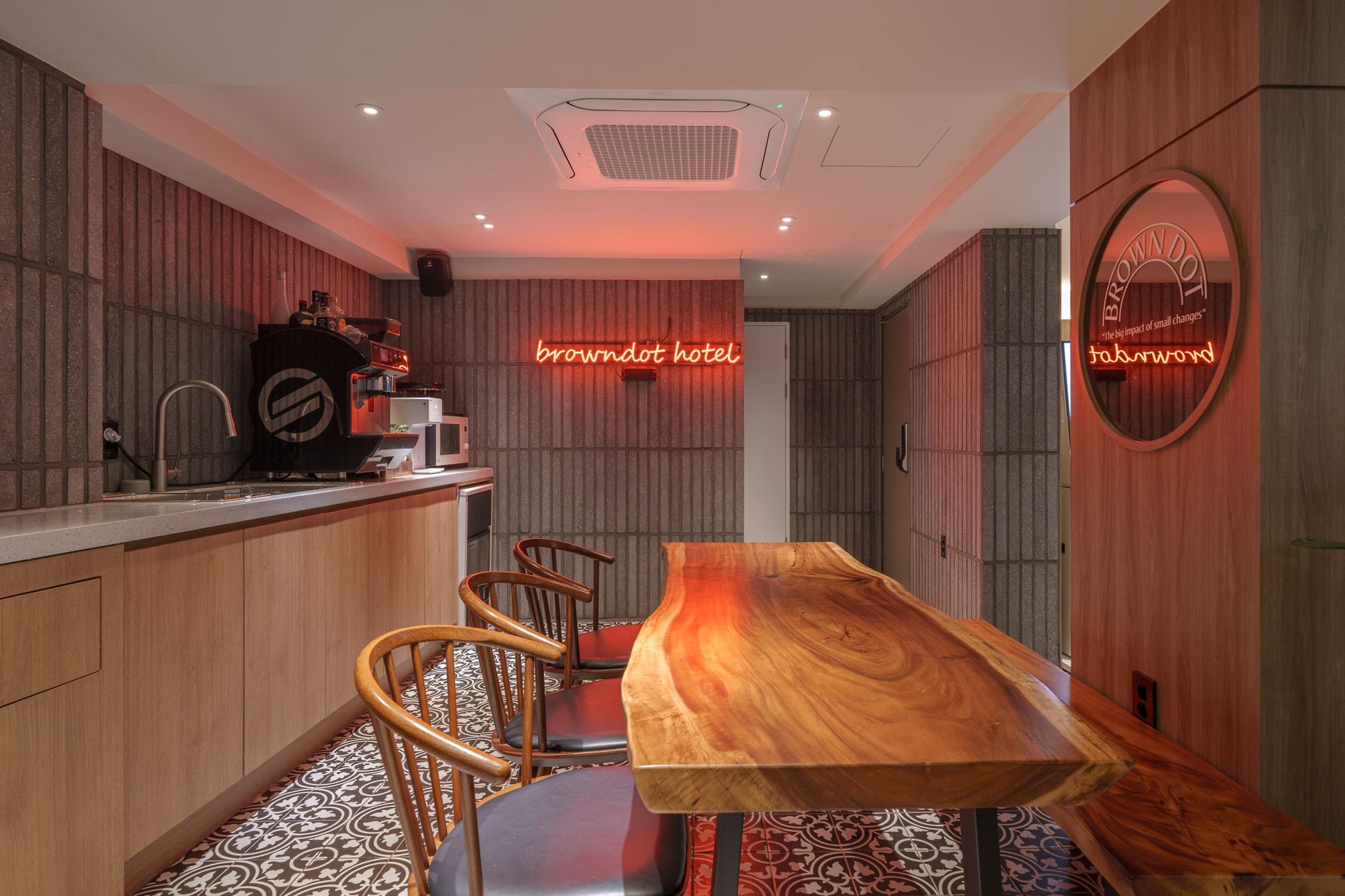 Uma cozinha moderna com mesa e cadeiras de madeira, um letreiro de neon e um piso estampado.