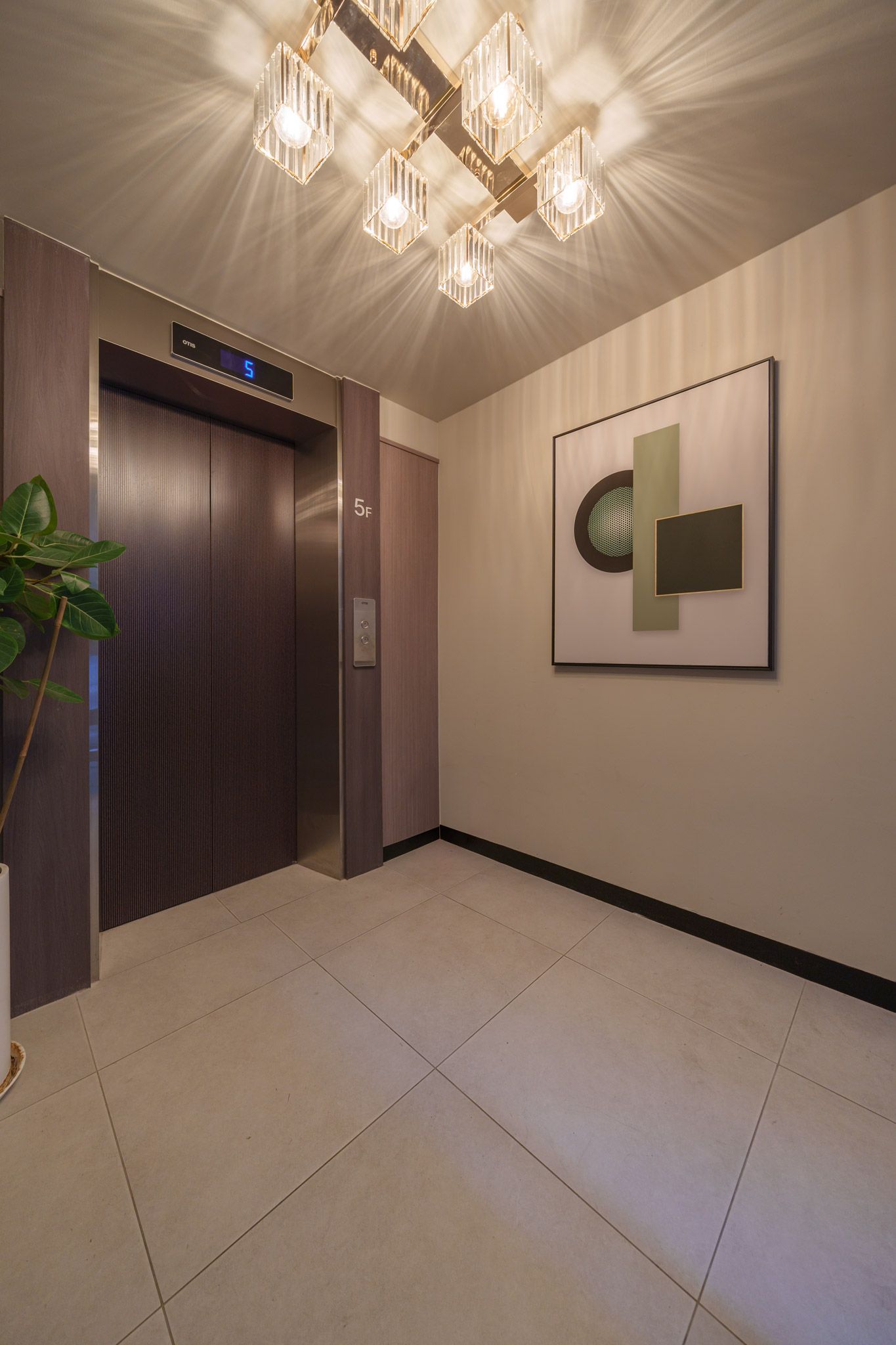 A modern elevator with a digital display, a wall-mounted artwork, and a potted plant.