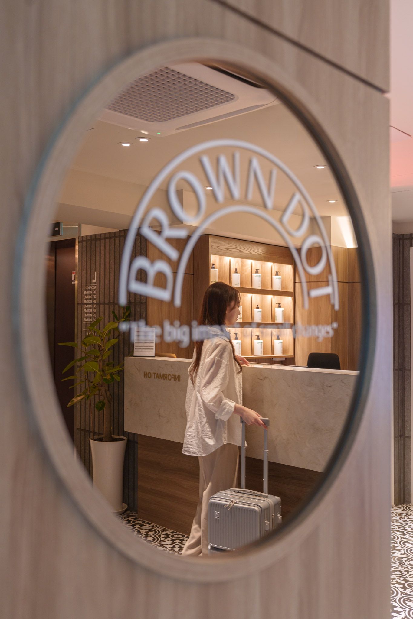 A person walking towards a reception desk with a sign that reads 'BROWN BOT'.