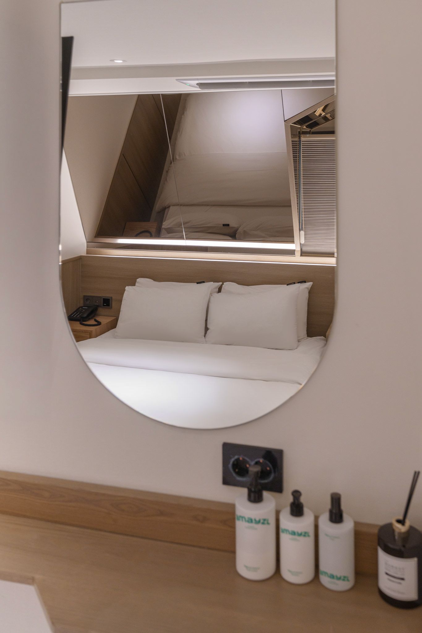 Une chambre à coucher avec un lit, un téléphone sur la table de chevet et un miroir au mur.