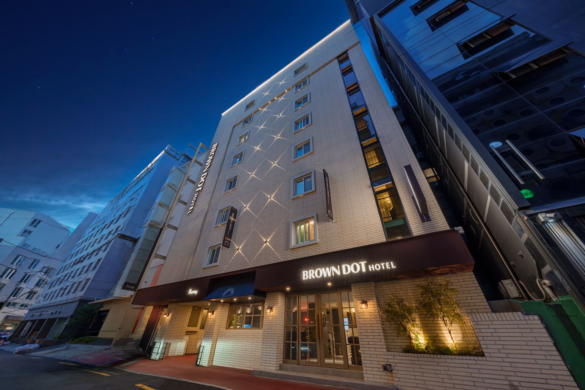 Un hôtel à plusieurs étages, reconnaissable à son enseigne bien visible, portant le nom de « Brown Dot Hotel ».