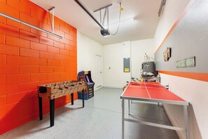 A room with a foosball table, a ping pong table, and a small arcade machine. - Next to Disney! 4/4 Townhome, Themed Rooms, 6 Beds (Kissimmee)