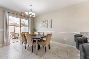 A dining area with a table and chairs, a chandelier, and artwork on the wall. - Next to Disney! 4/4 Townhome, Themed Rooms, 6 Beds (Kissimmee)