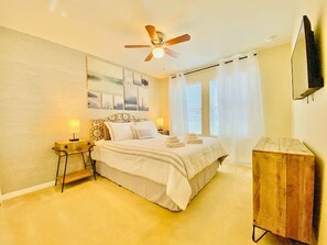 A bedroom with a bed, bedside tables, a ceiling fan, and a TV mounted on the wall. - Next to Disney! 4/4 Townhome, Themed Rooms, 6 Beds (Kissimmee)