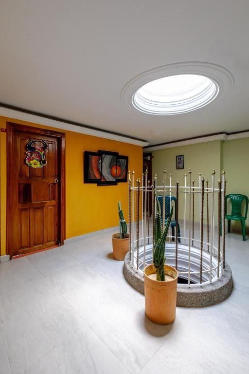 Een kamer met een houten deur, een ronde lamp en potplanten.