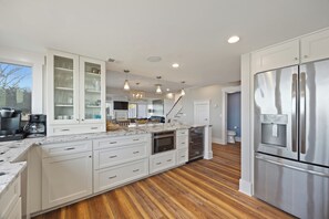 Eine moderne Küche mit weißen Schränken, einem Edelstahlkühlschrank und einem Holzboden.