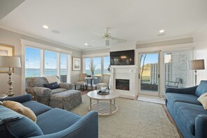 A spacious living room with a fireplace, a television, and a view of the outdoors. - 722 Schooner Court at The Sea Pines Resort (Hilton Head Island)