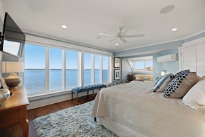 A bedroom with a large bed, a view of the water, and a ceiling fan. - 722 Schooner Court at The Sea Pines Resort (Hilton Head Island)