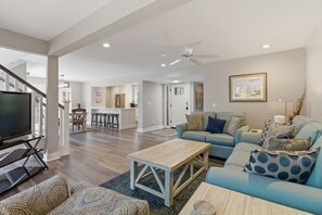 A spacious living room with a large television, a sofa set, a coffee table, and a dining area in the background. - 2425 Inland Harbour at The Sea Pines Resort (Hilton Head Island)