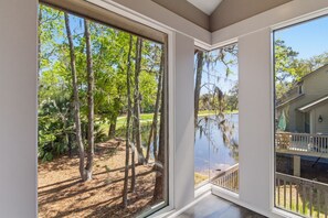 A room with large windows overlooking a wooded area and a body of water. - 2425 Inland Harbour at The Sea Pines Resort (Hilton Head Island)