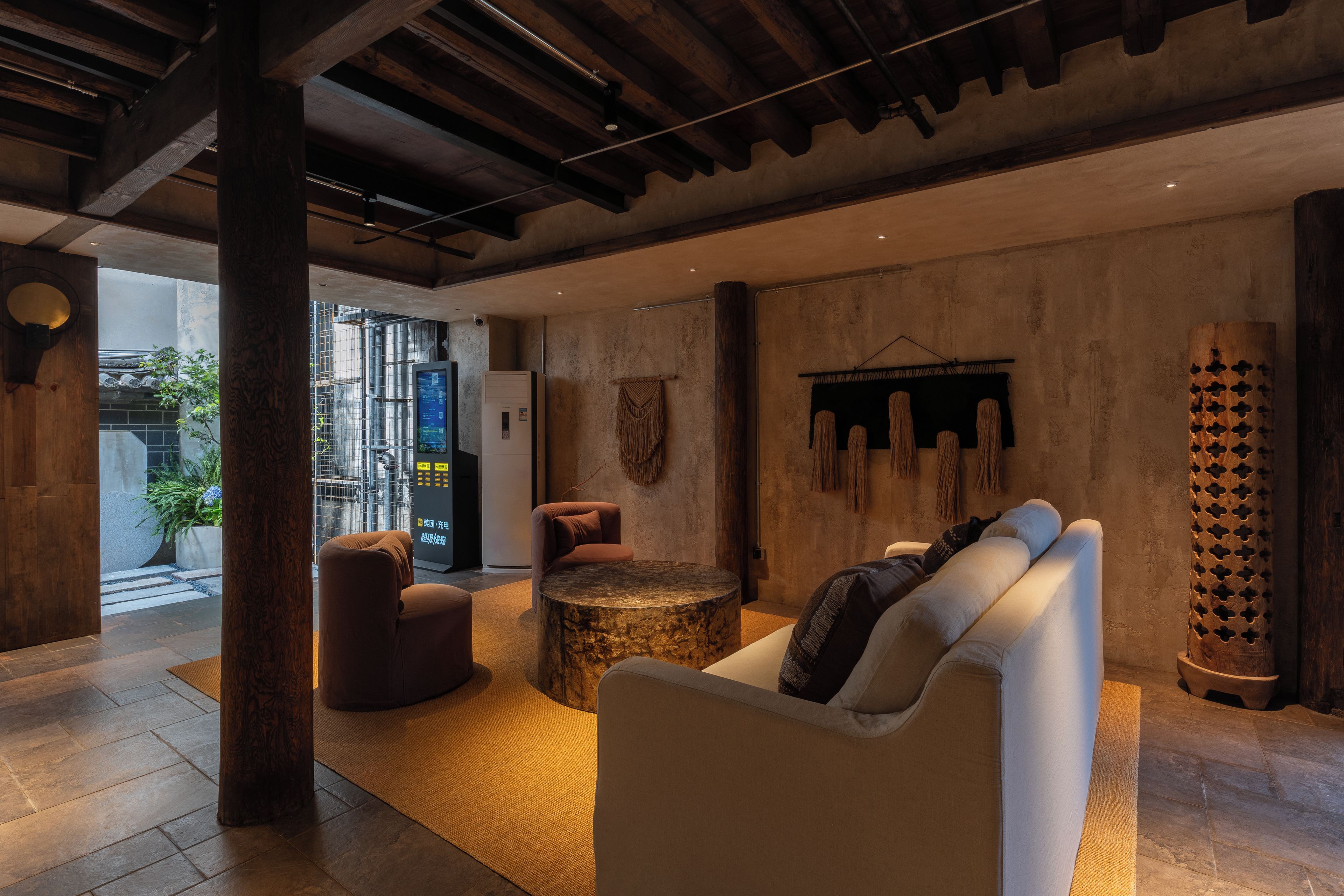 A modern interior with a seating area, a round table, and a large wooden column.