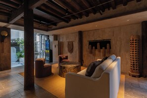 Un interior moderno con una zona de estar, una mesa redonda y un gran pilar de madera.