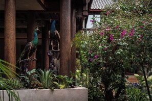 A traditional building with wooden pillars and a garden with various plants and flowers.