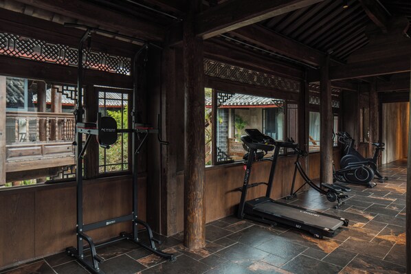 A gym with exercise equipment, wooden beams, and large windows.