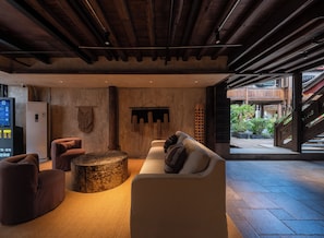 Un interior modern amb un sostre de fusta, una zona d'estar amb una taula rodona i vista a un balcó exterior.