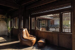 A room with a leather chair, a small ottoman, and a large window with traditional lattice design. - Arcadia Coffee Lounge Courtyard Design Homestay - Lijiang Old Town - European Industrial Style Meets Intangible Cultural Heritage Chinese Courtyard (Lijiang)