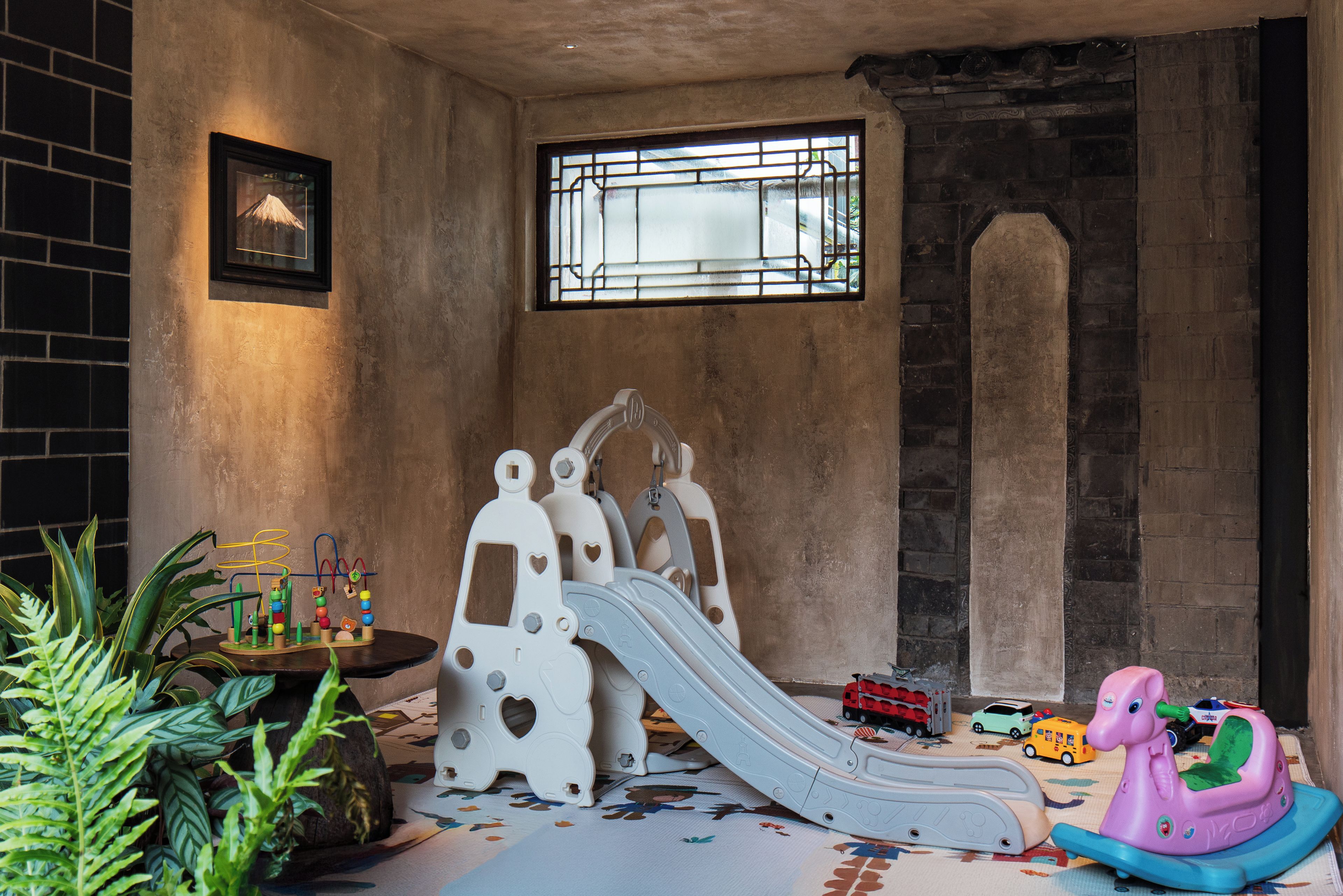 Un espace de jeux avec un toboggan, des jouets et une fenêtre.