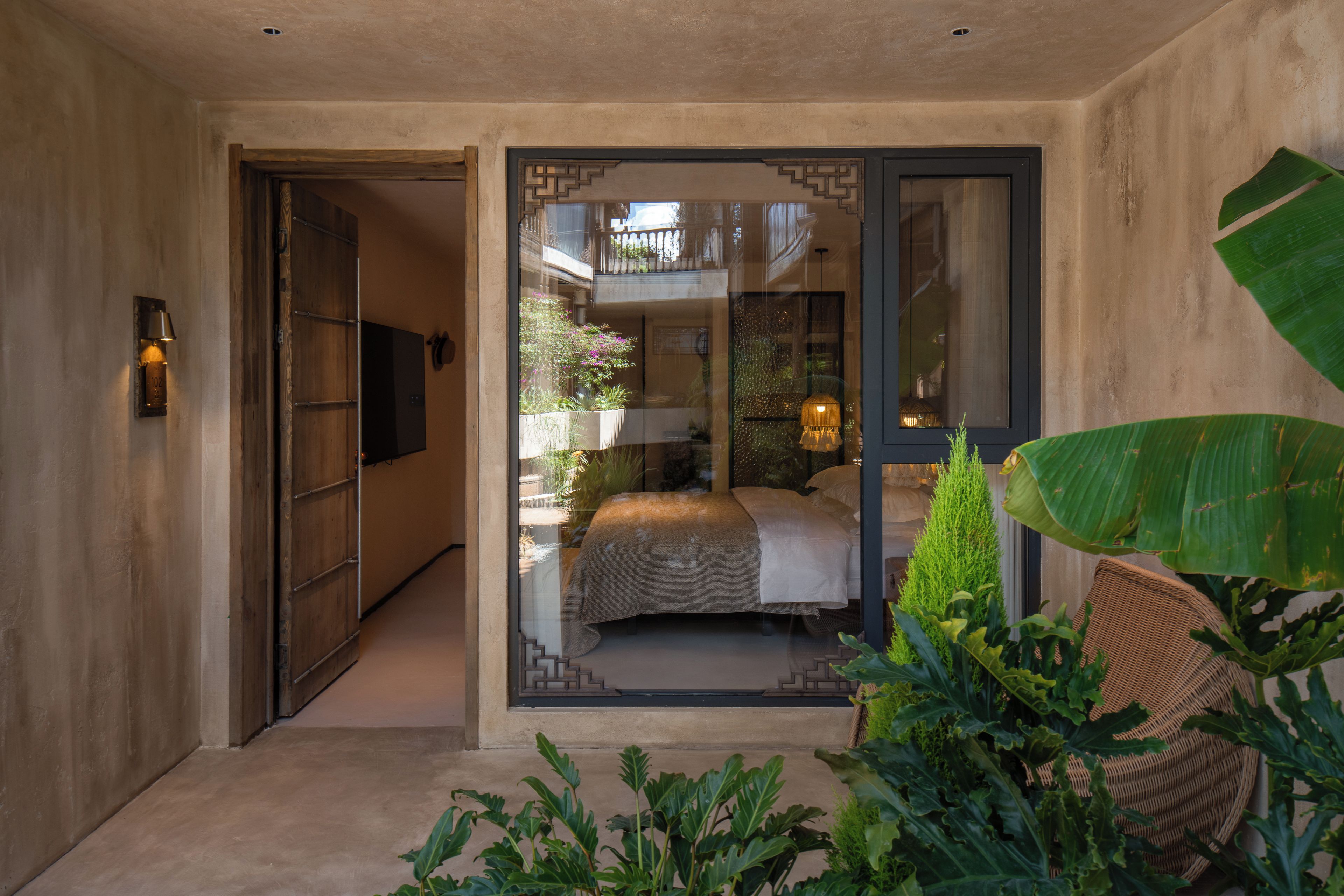 Een moderne slaapkamer met een groot bed, een balkon met planten en uitzicht op de omgeving.
